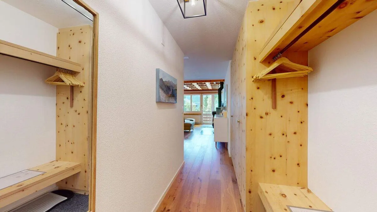 Eingangsbereich mit Garderobe aus Arvenholz und Blick in den Flur