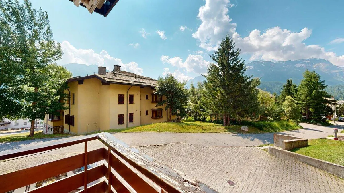 Hof mit Rasen, Tannen und Nachbarhaus vor den Bergen