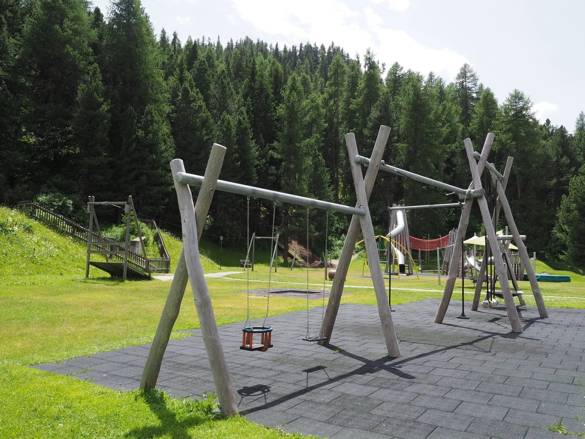 Swings and climbing frames at the St. Moritz playground at the edge of the forest