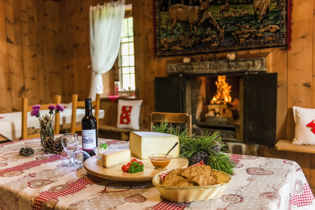 Gedeckter Tisch mit Käse und Brot vor dem Kaminfeuer im Alp Beizli Laret