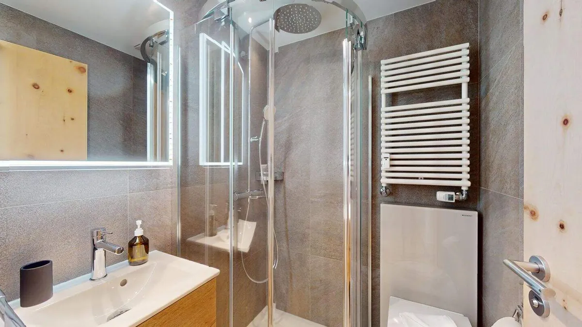 Dusche/WC mit Glasdusche, Handtuchheizkörper und Lavabo
