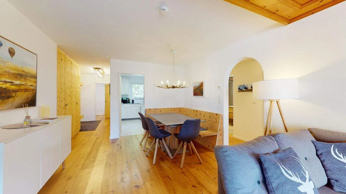 Essbereich mit Holztisch, Eckbank und Leuchter, rechts das Sofa
