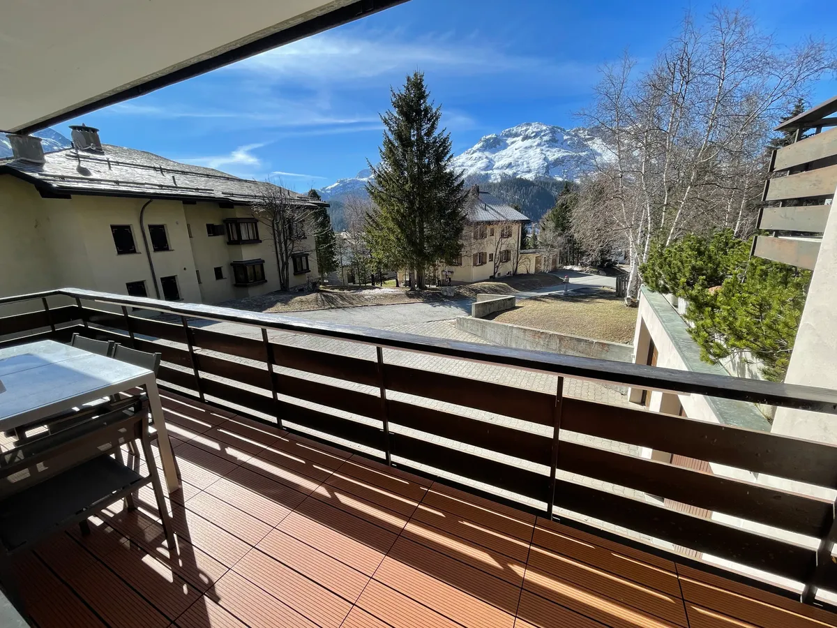 Balkon mit Blick auf Nachbarhäuser, Tannen und Berge