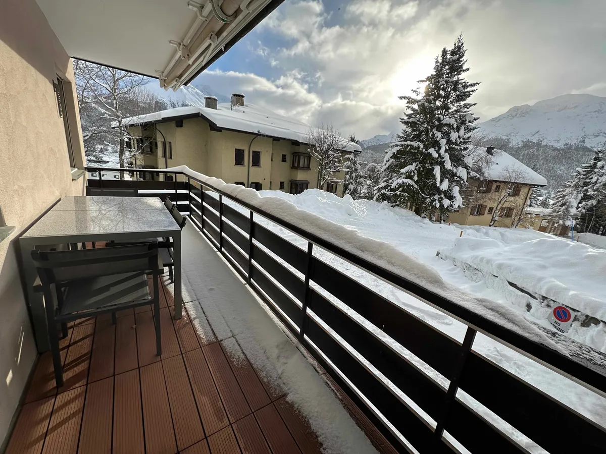 Verschneiter Balkon mit Blick auf Häuser und Berge im Winter