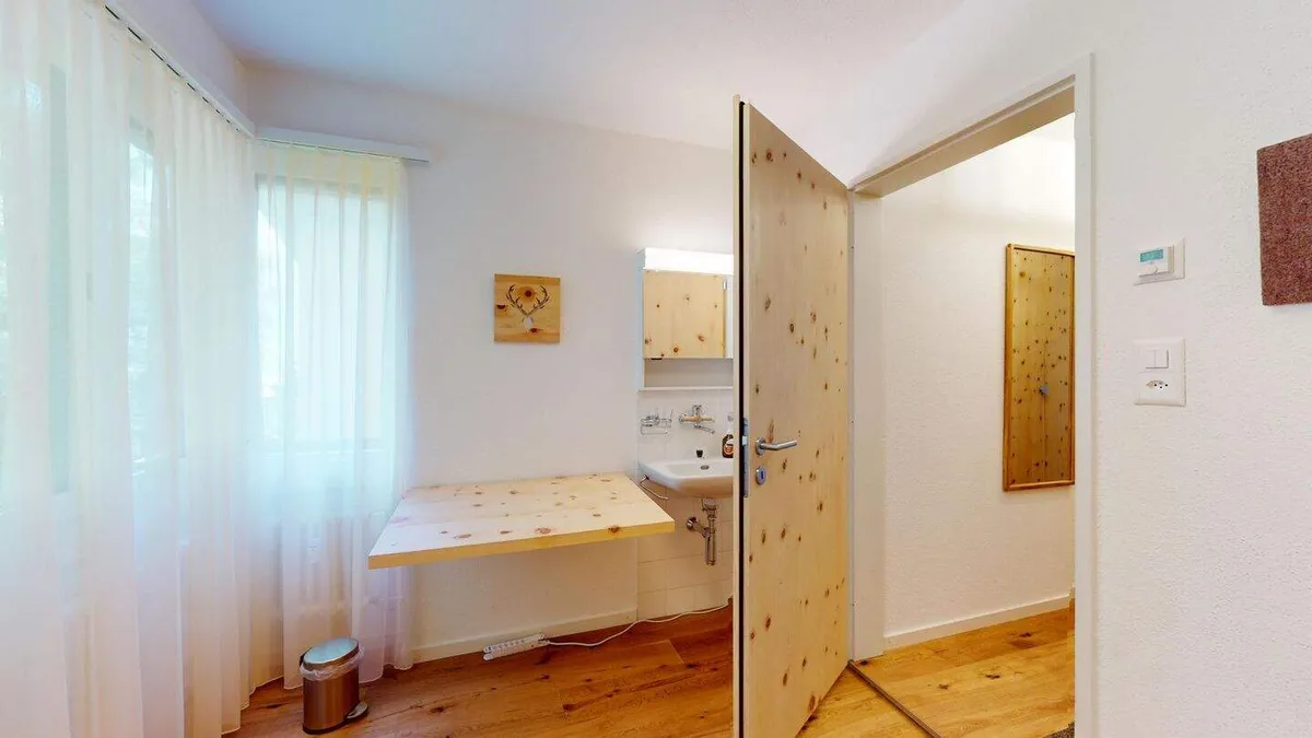 Bürozimmer mit Arbeitsplatz am Fenster und Arventür