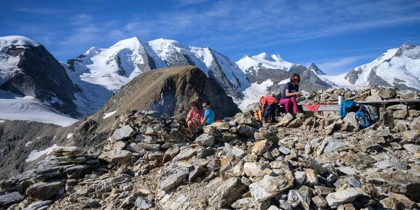 Hikers at the fire pit on the Sass Queder in front of the Bernina massif