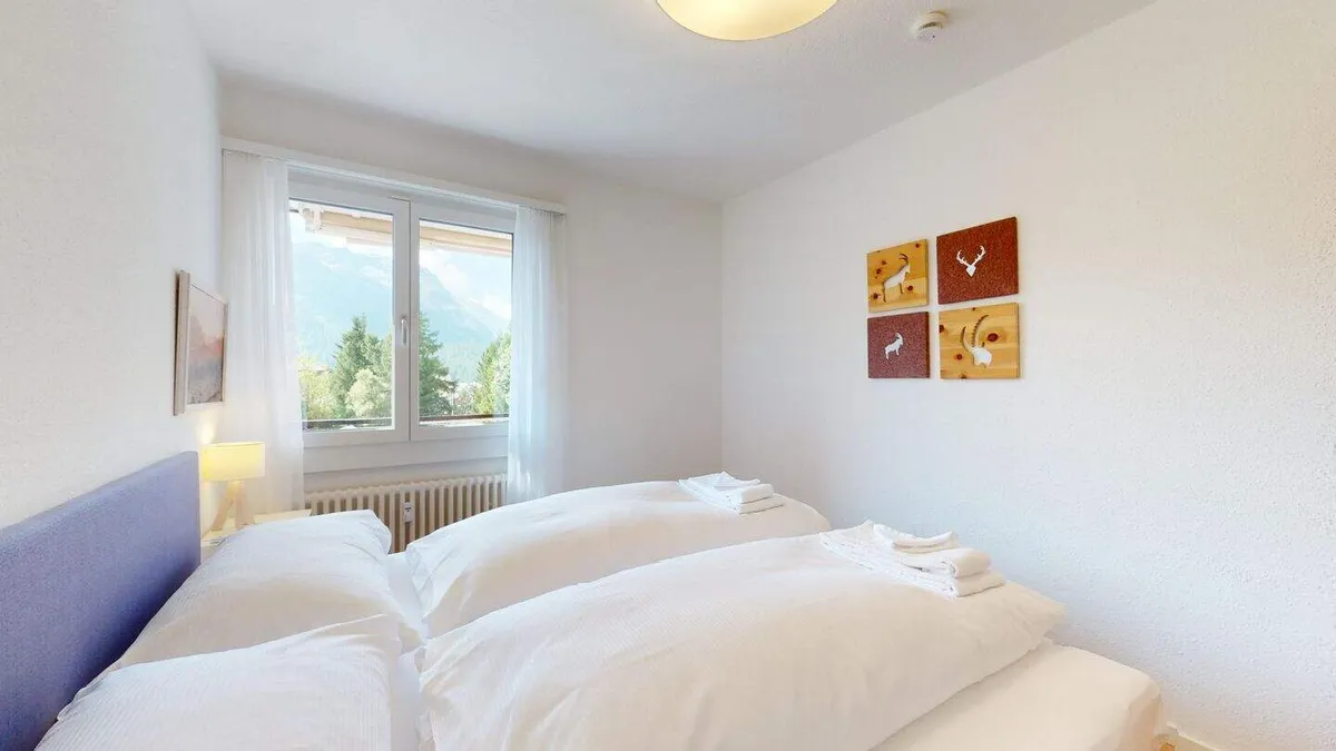 Schlafzimmer mit Doppelbett, weisser Bettwäsche und Fenster