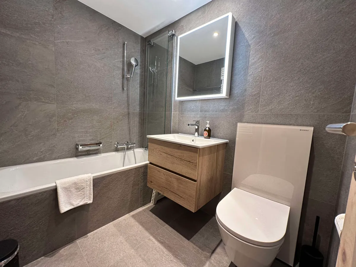 Renoviertes Badezimmer mit Badewanne, Lavabo und WC