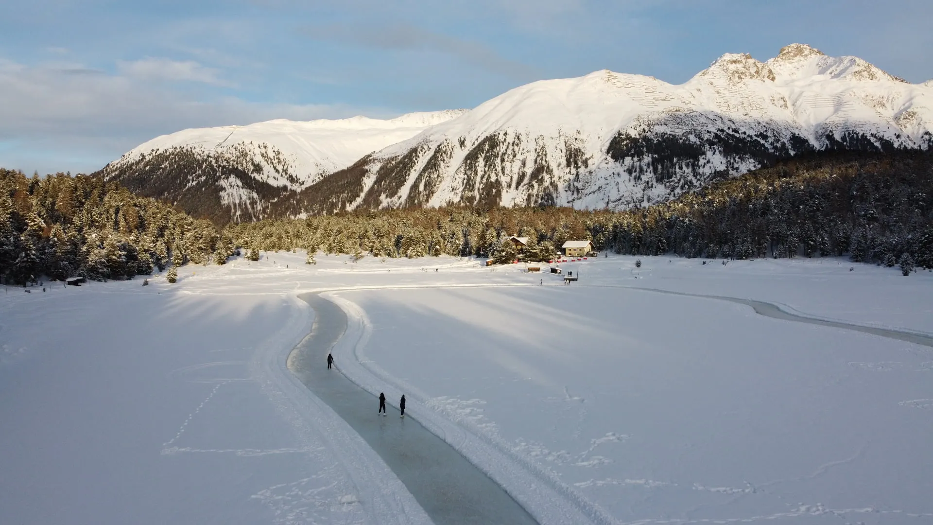 Eisbahn auf dem verschneiten Stazersee vor den Bergen