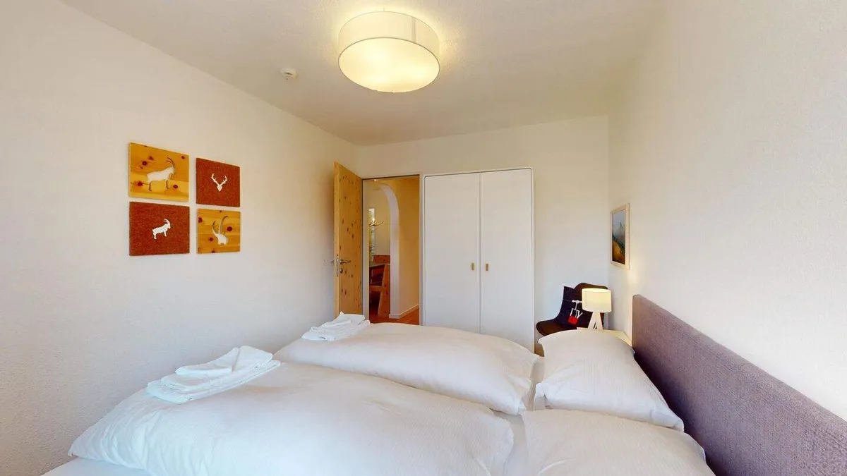 Schlafzimmer mit Doppelbett, Kleiderschrank und Hirschbildern an der Wand
